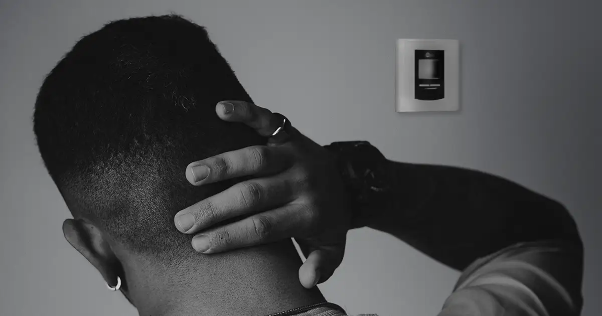A man stressing out over the blank screen on his HVAC thermostat.