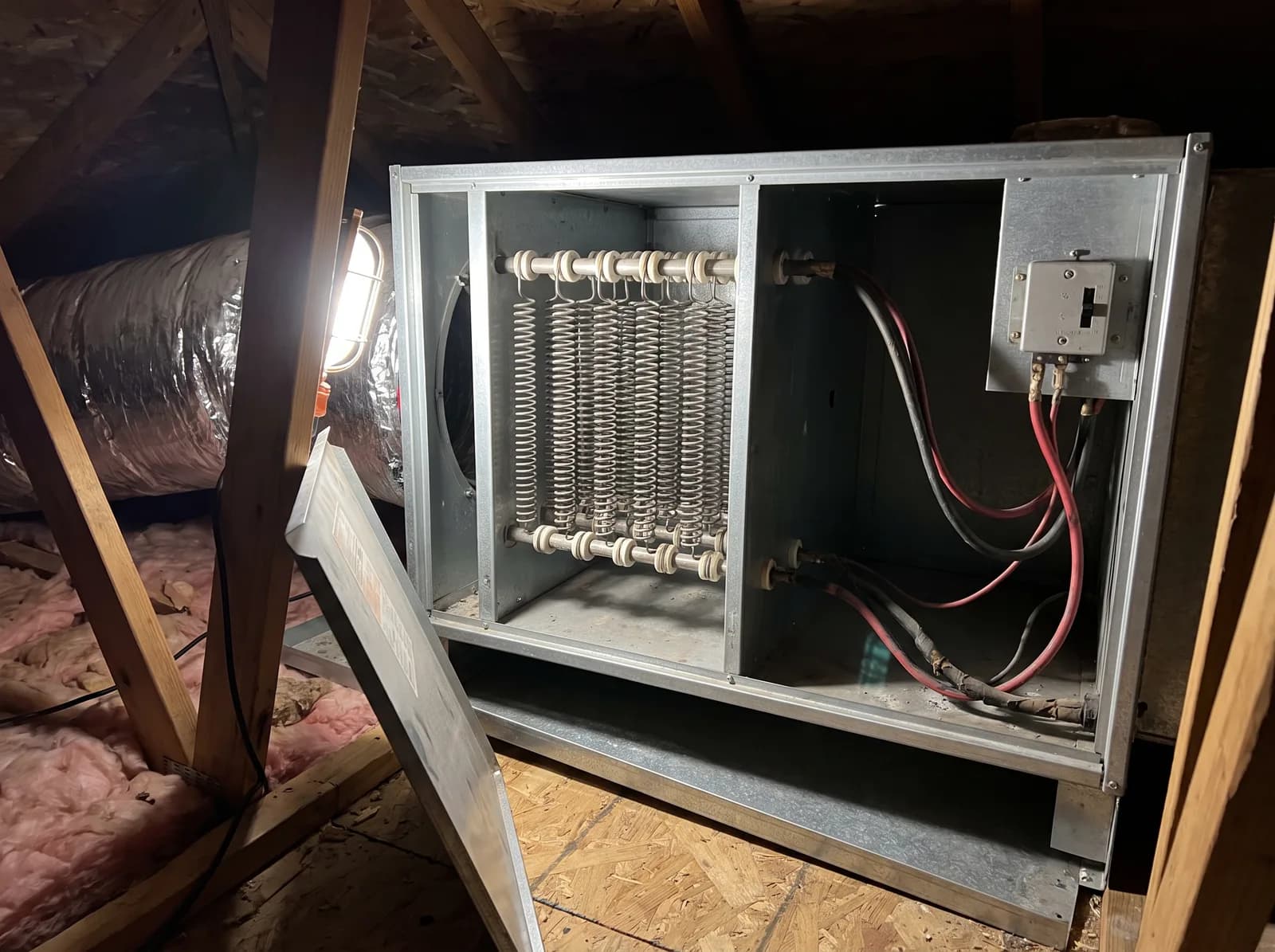 An A/C Rescue technician testing the electric heat strip terminals inside an opened air handler with a clamp meter